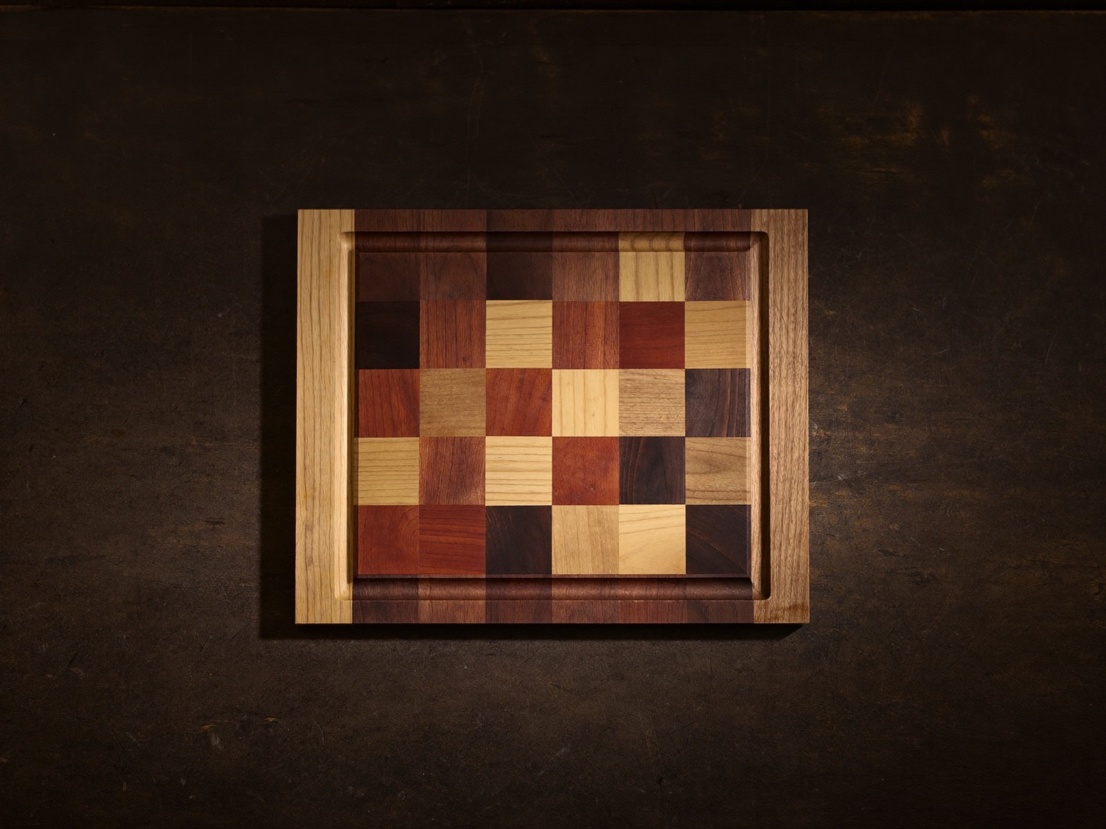 The Carver seen square-on from above: an end-grain mosaic with a juice channel routed around the whole perimeter, inside a mitred walnut border.