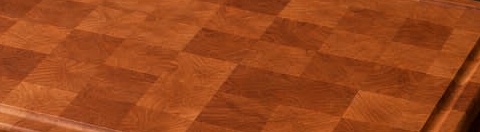 The end-grain surface of a finished cherry board: a warm red-amber chequer with a fine, even grain.