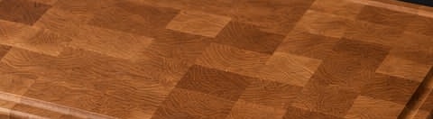 The end-grain surface of a finished oak board: a mid golden-brown chequer with open, visible pores.